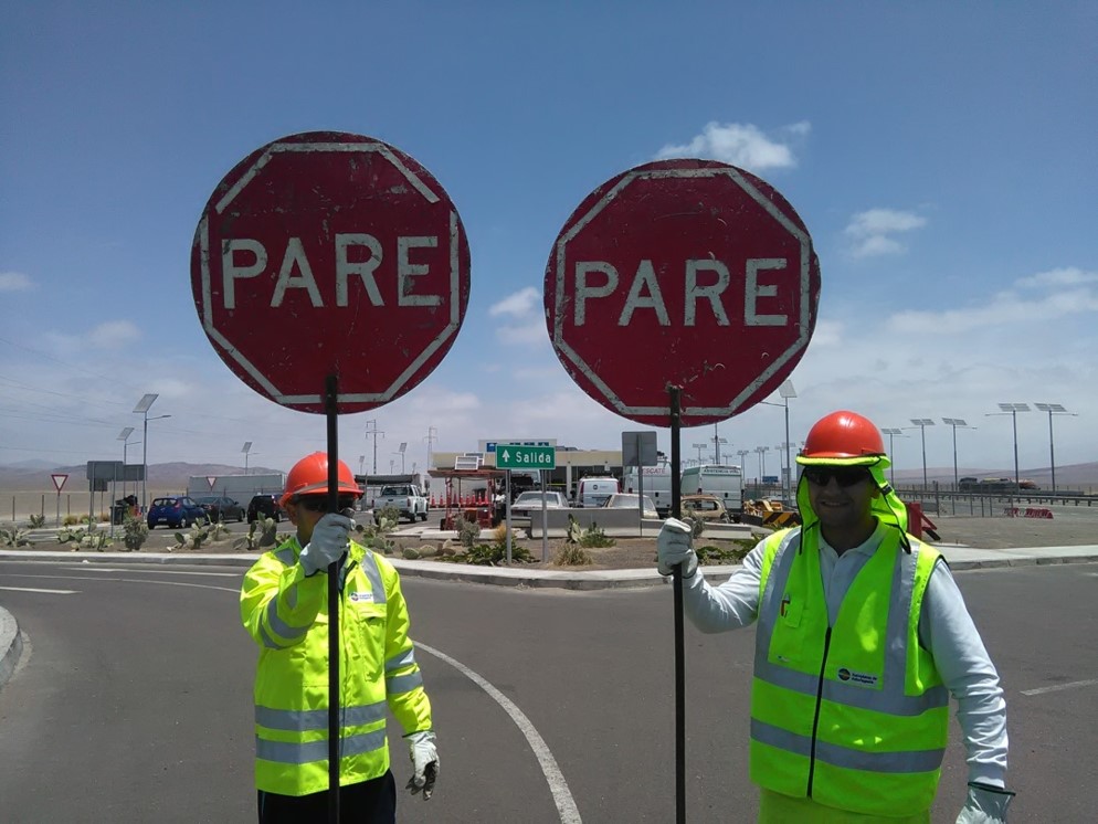 Bandereros con señales PARE en una zona vial